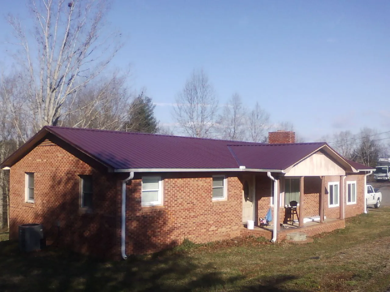 Burgundy metal roof on a brick ranch home with a new addition in Thomson