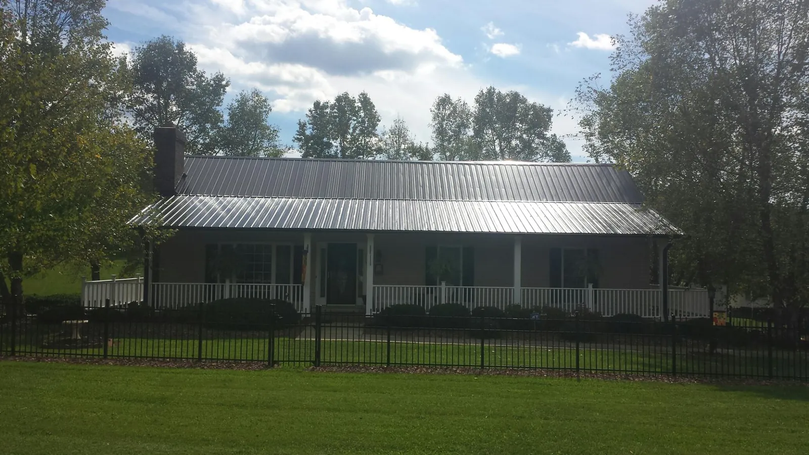 Gray metal roof on a brick ranch with a full width front porch — Gutter Guard Installation work by our crew in Thomson